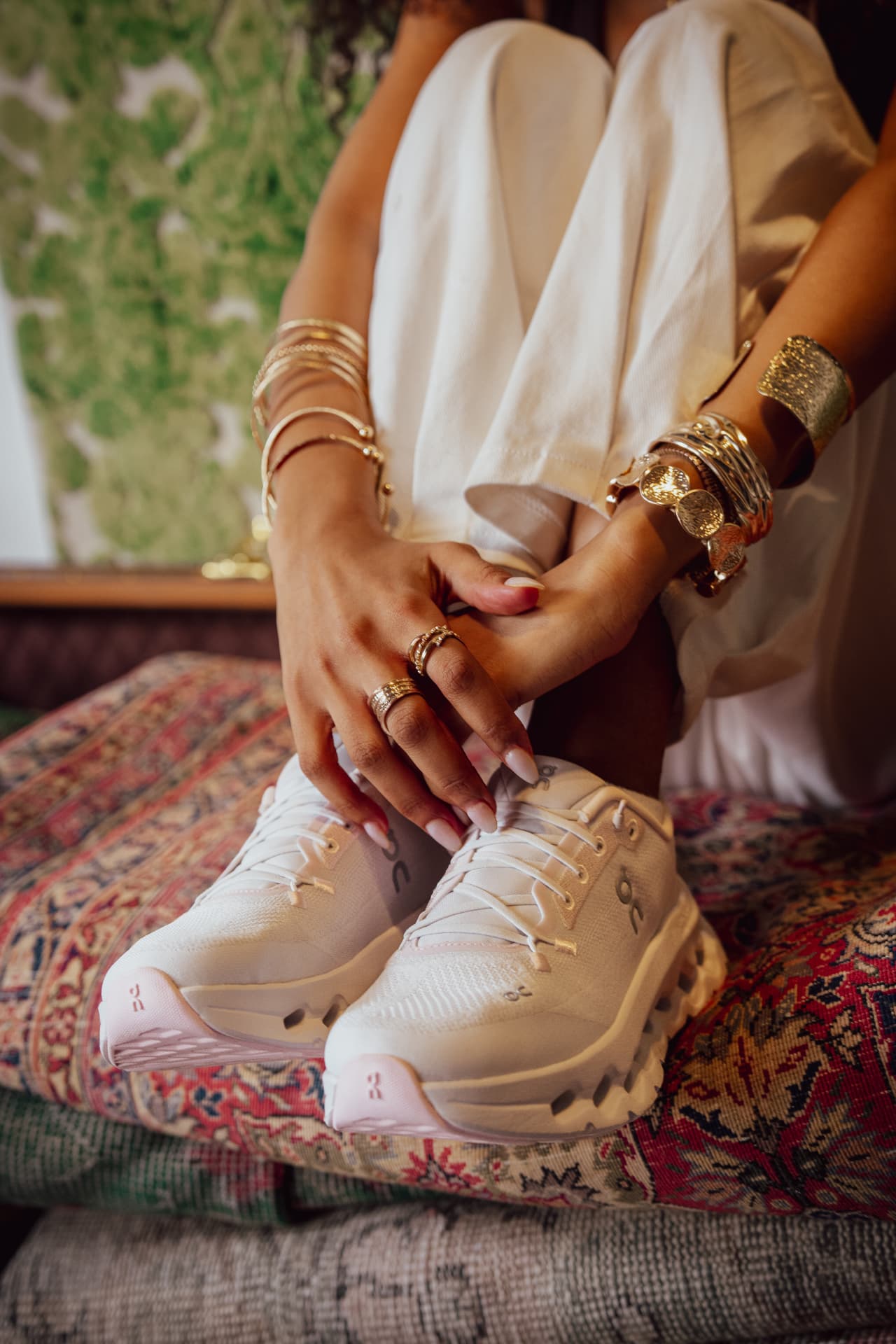 Hands and white sneakers on a patterned rug