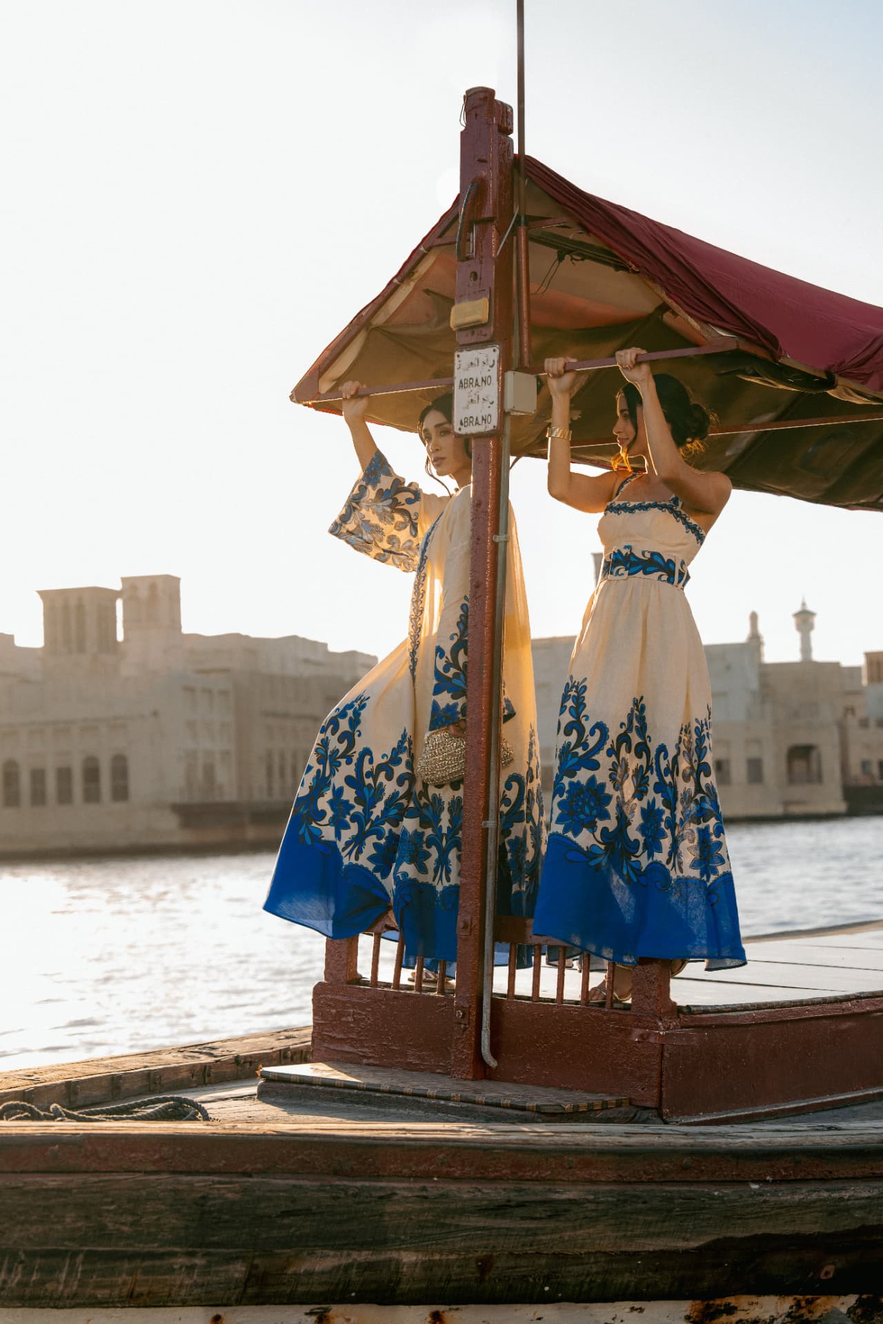 Two women in blue and white dresses on an abra on the creek