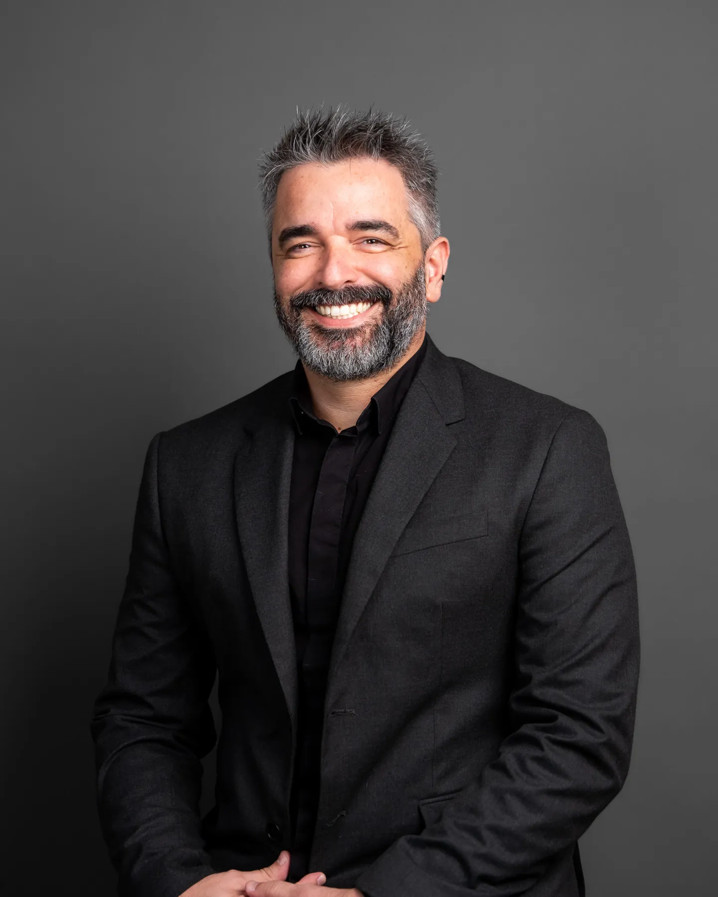 Professional portrait of a bearded man in black