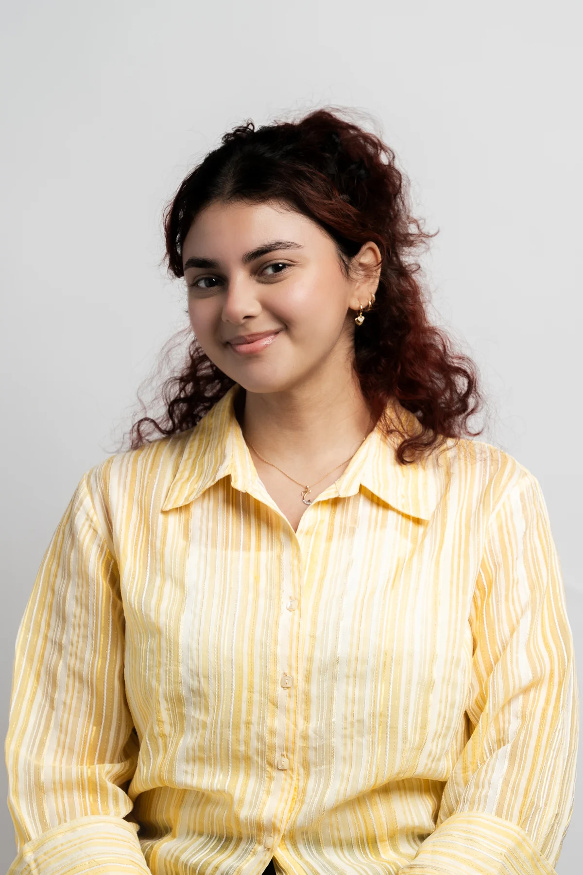 Young woman with red curly hair in a yellow striped shirt
