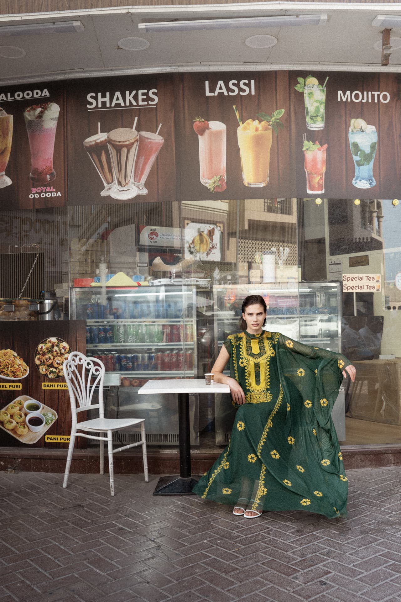 Model in green embroidered kaftan outside a juice bar