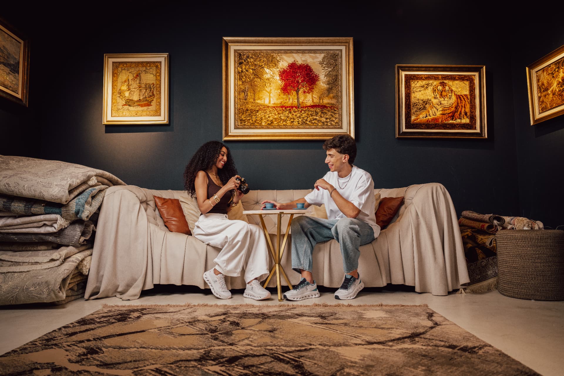 Two models chatting on sofas in a gallery of paintings