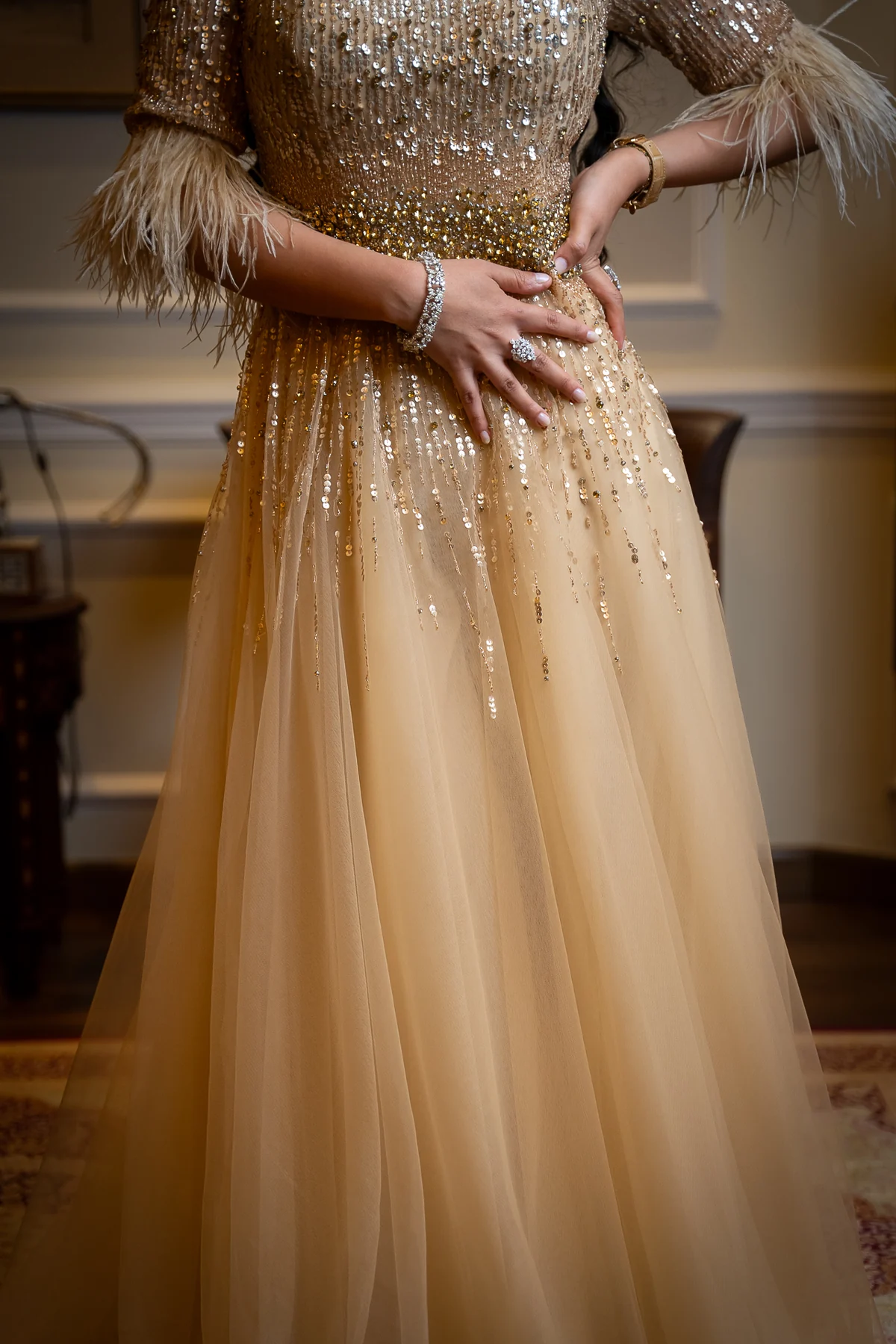 Bride in a gold sequined gown with feathered sleeves