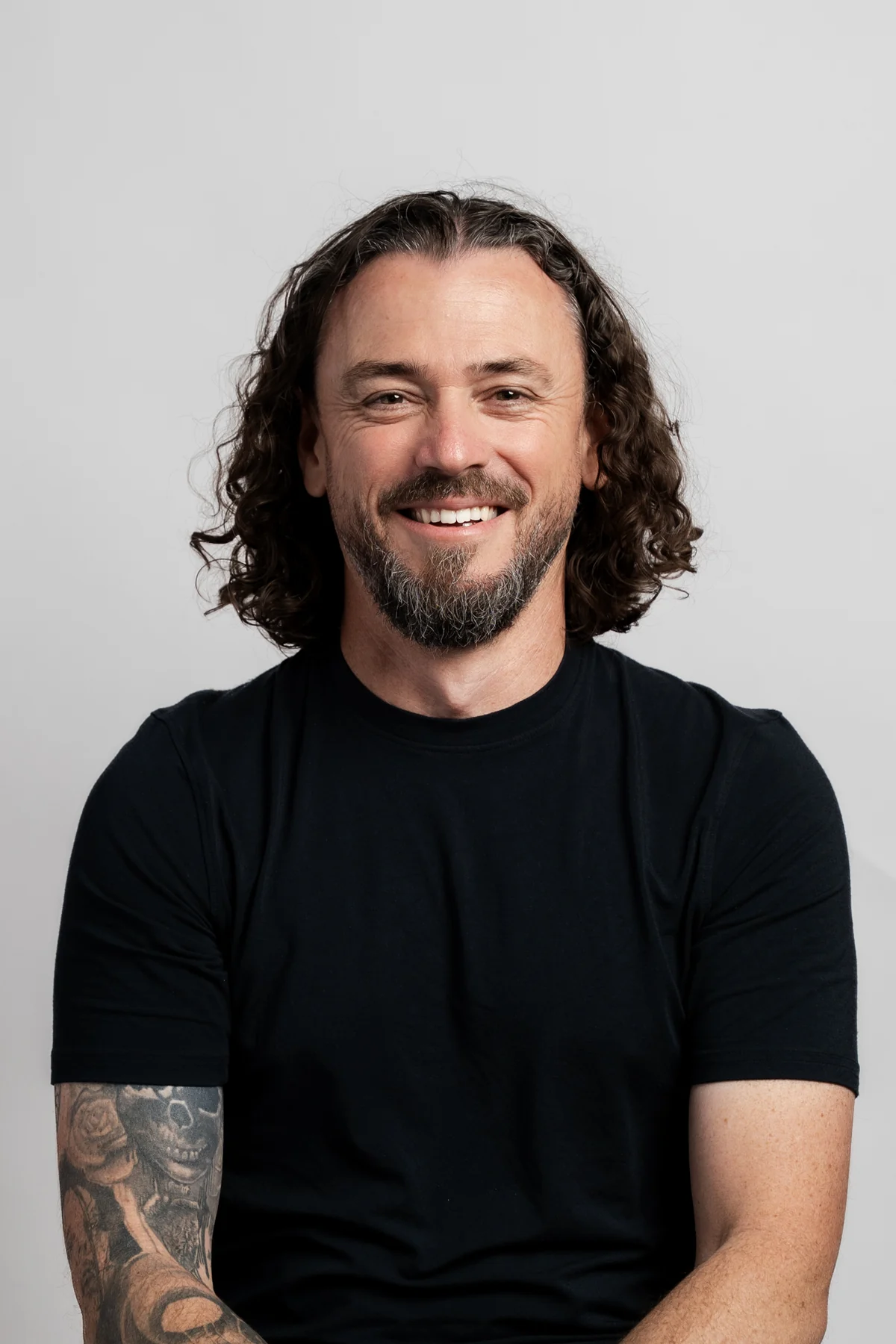 Smiling man with long curly hair in a black t-shirt