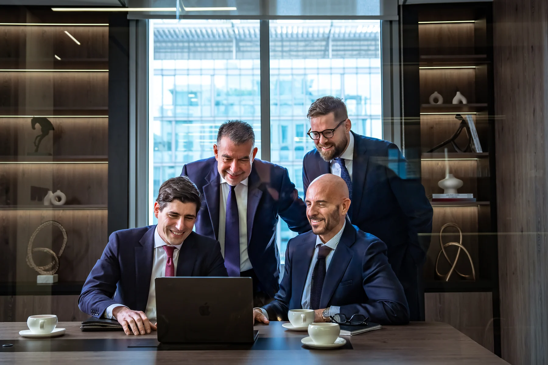 Team of lawyers gathered around a laptop in a boardroom