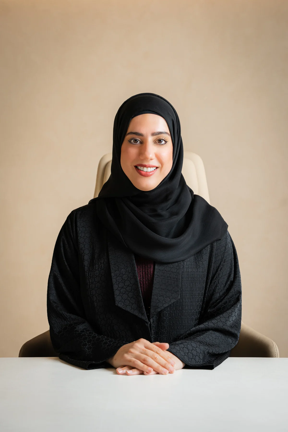 Emirati businesswoman in a black abaya seated at a white desk