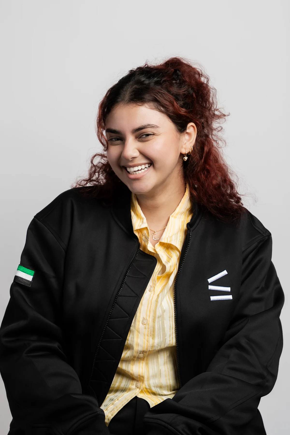 Young woman with red curly hair laughing in a black company jacket