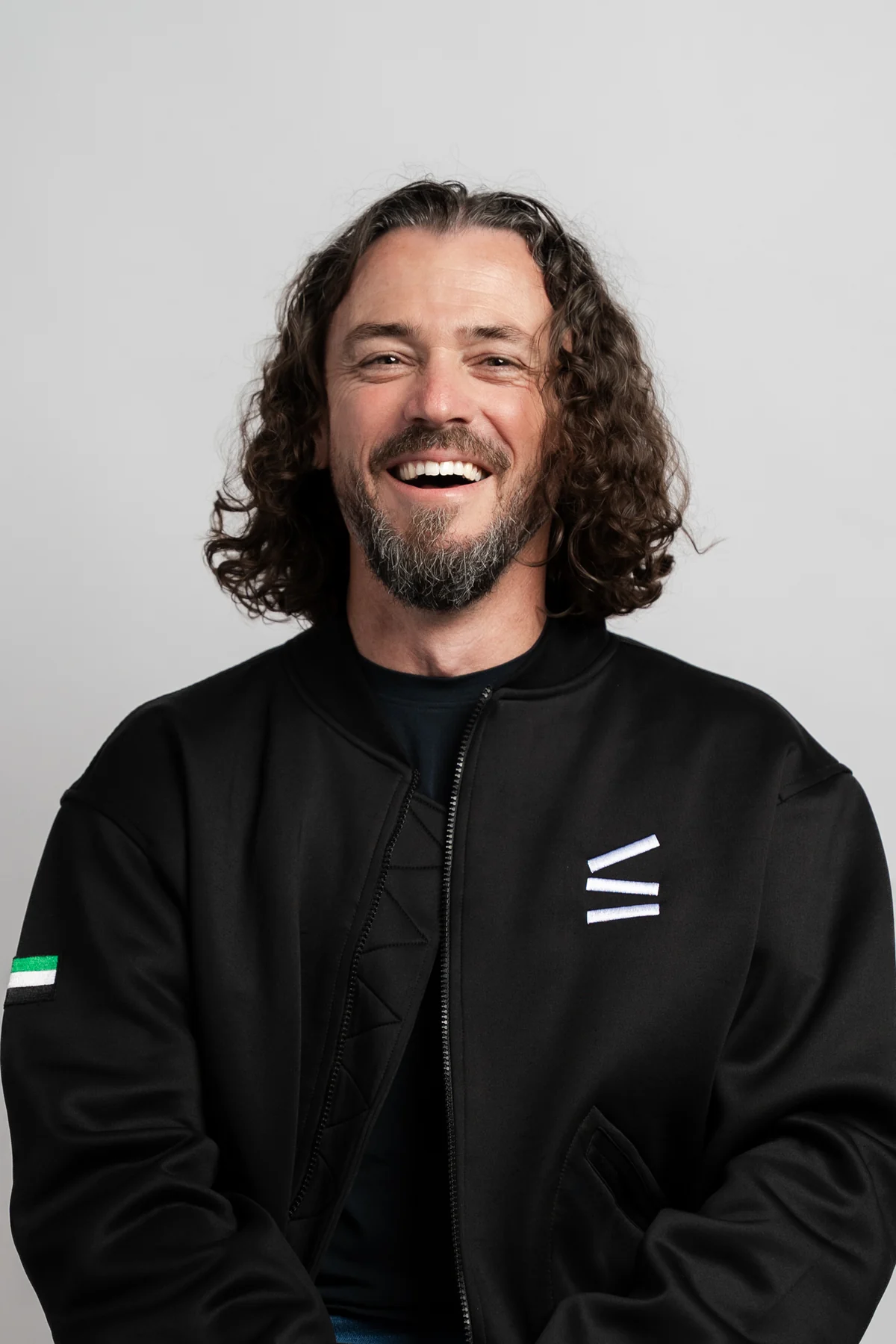 Laughing man with curly hair in a black company jacket