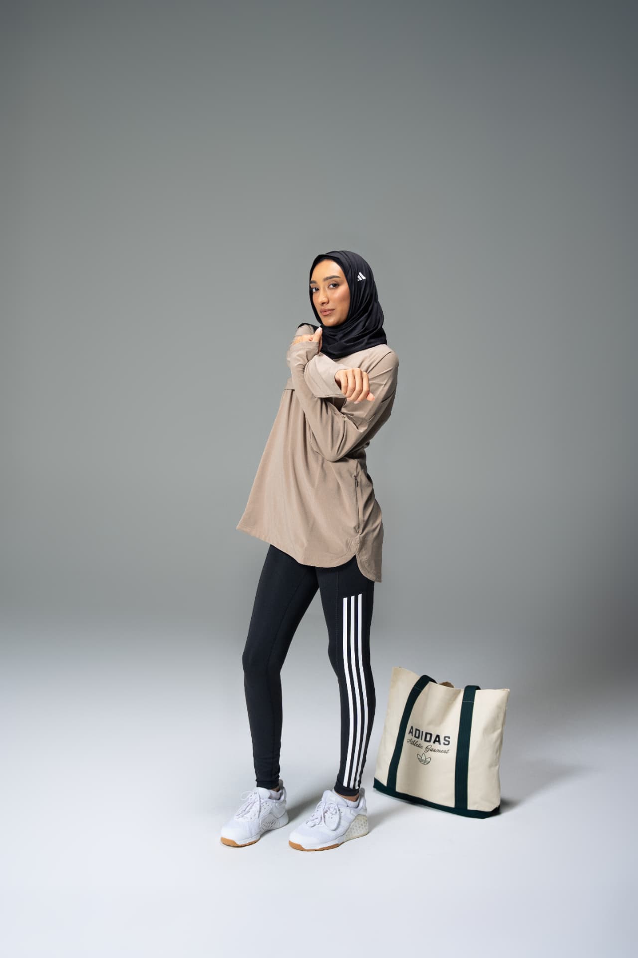 Woman in hijab and Adidas leggings beside a tote bag