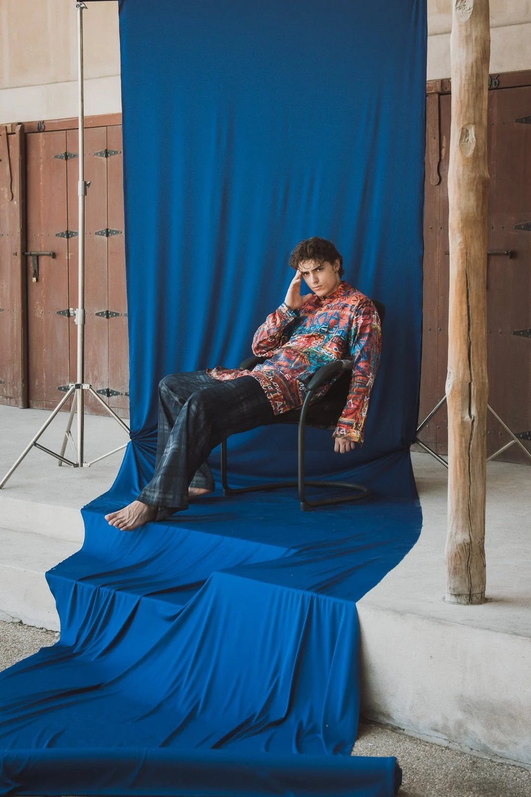 Model lounging on a chair over a blue backdrop