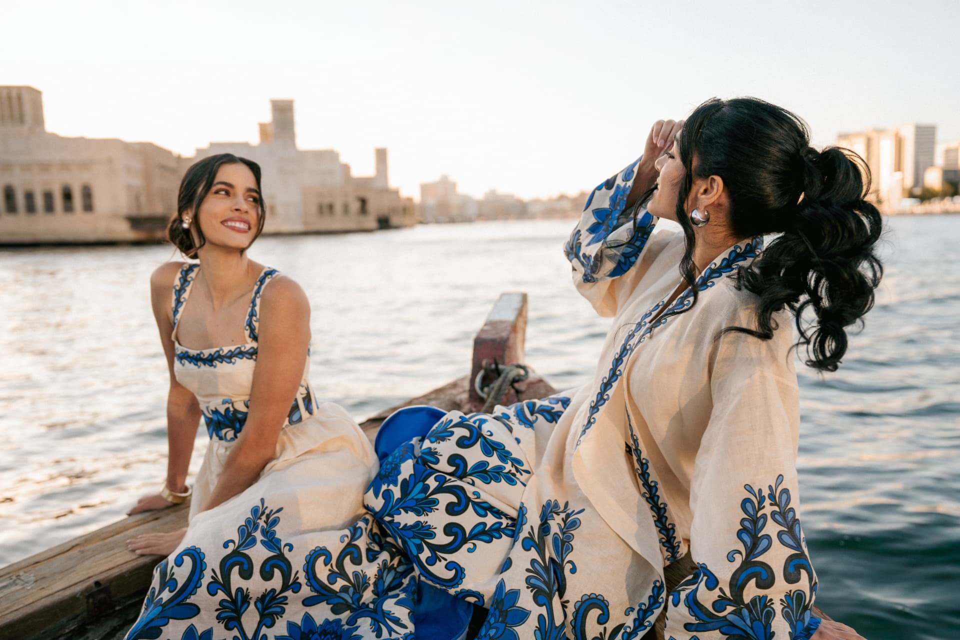 Two women in blue and white laughing on an abra on the creek