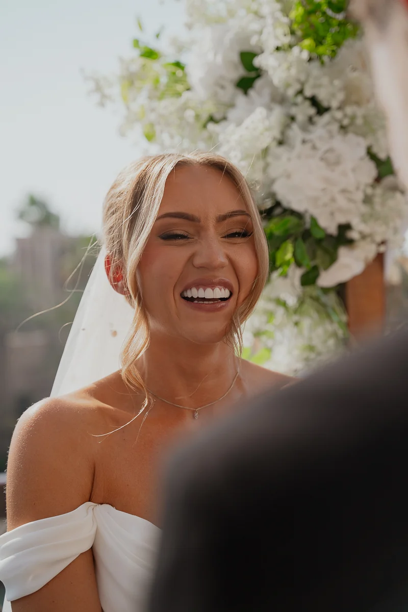 Bride laughing under white flowers
