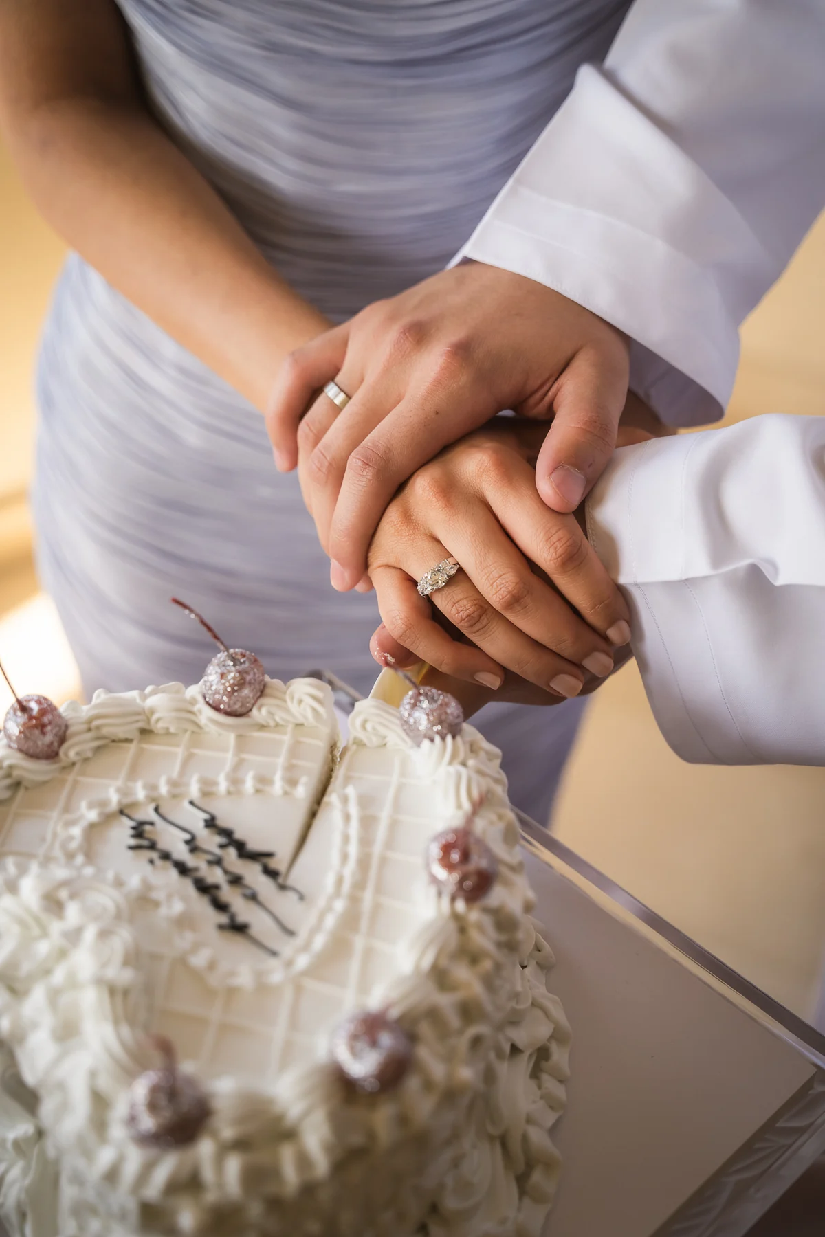 Couple's hands together cutting the cake