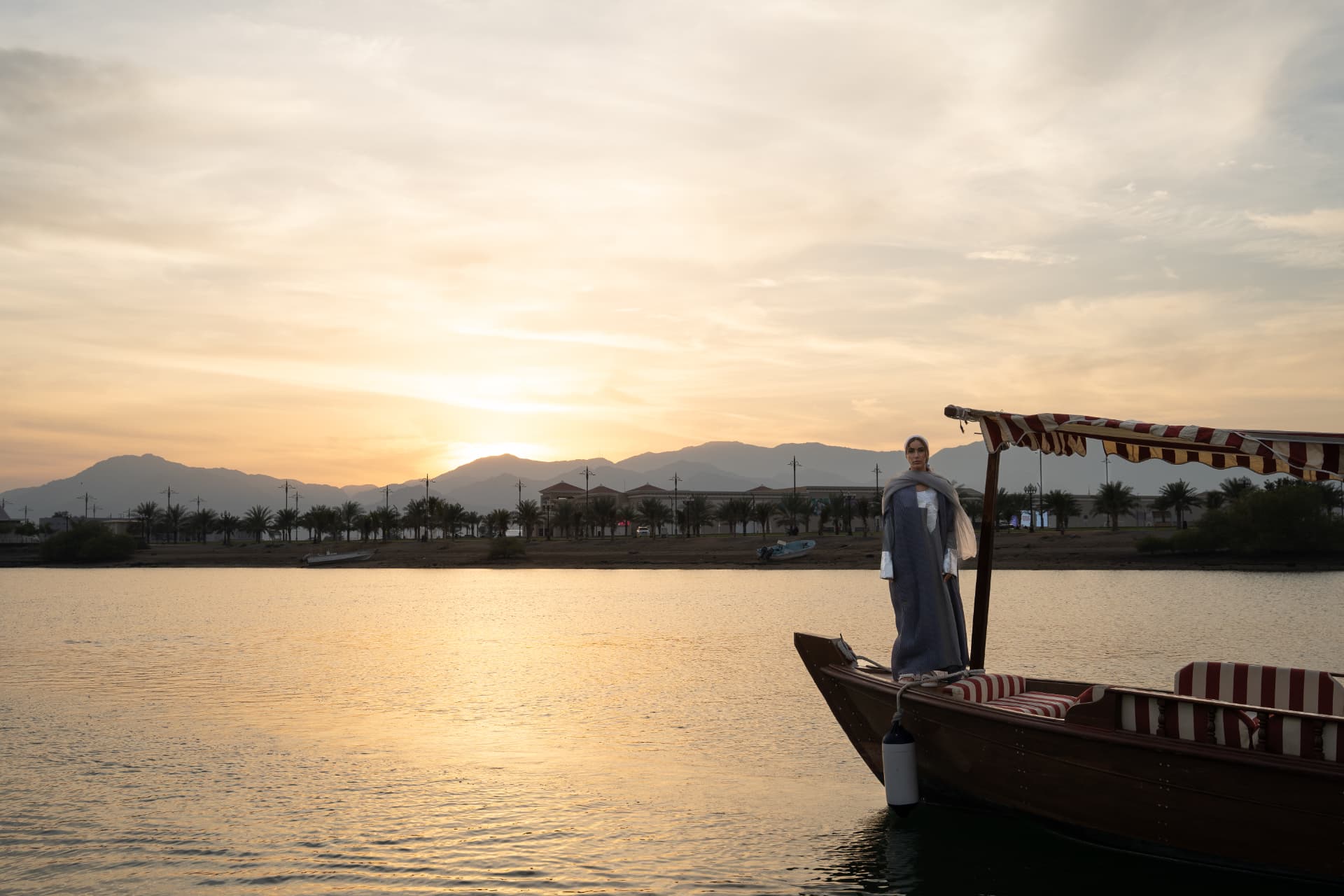 Man standing on an abra at sunset over the water