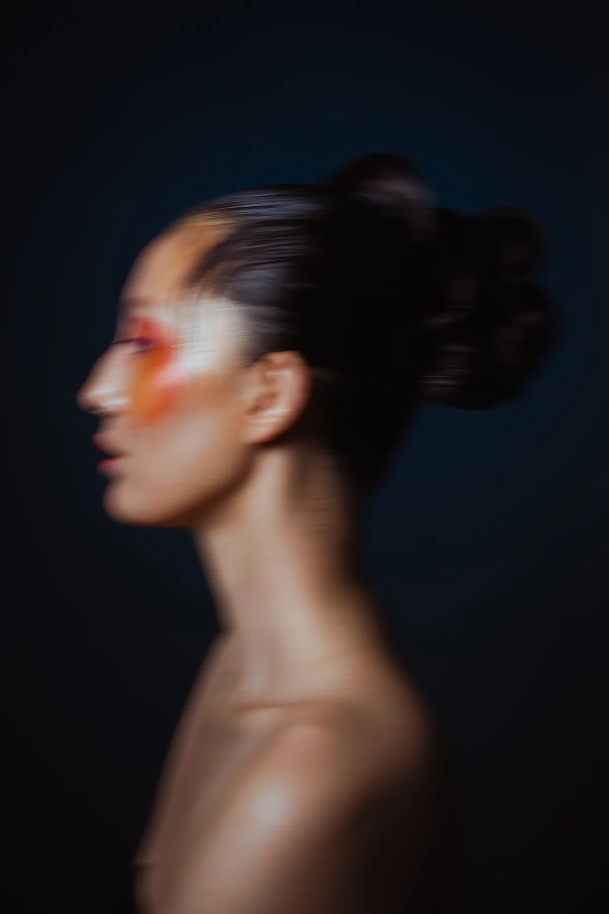 Profile with orange eye make-up against dark blue