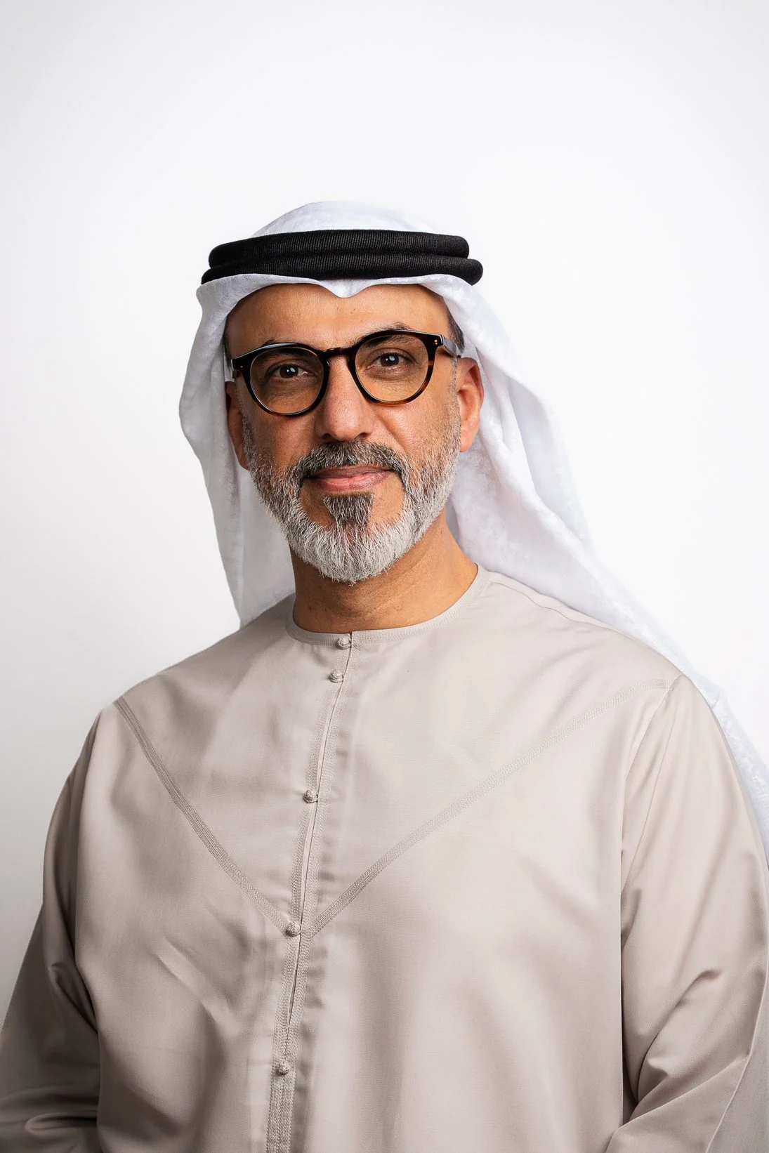 Corporate headshot of an Emirati man in glasses and a beige kandura