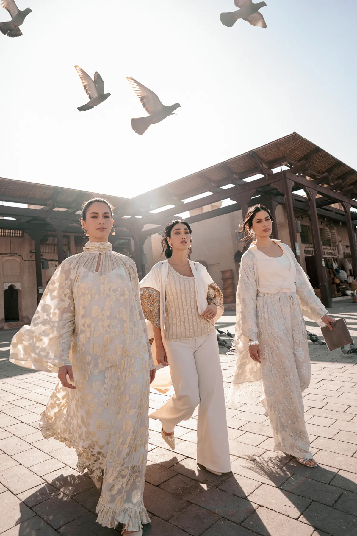 Three women in white with birds overhead