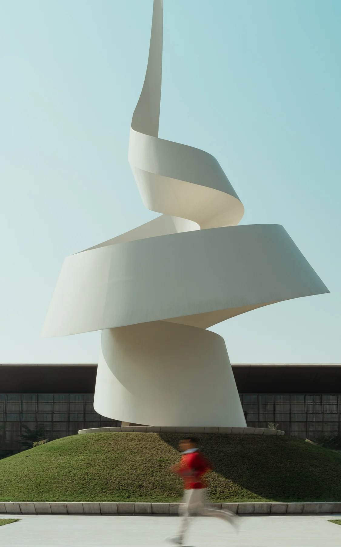 White spiral sculpture with a runner passing