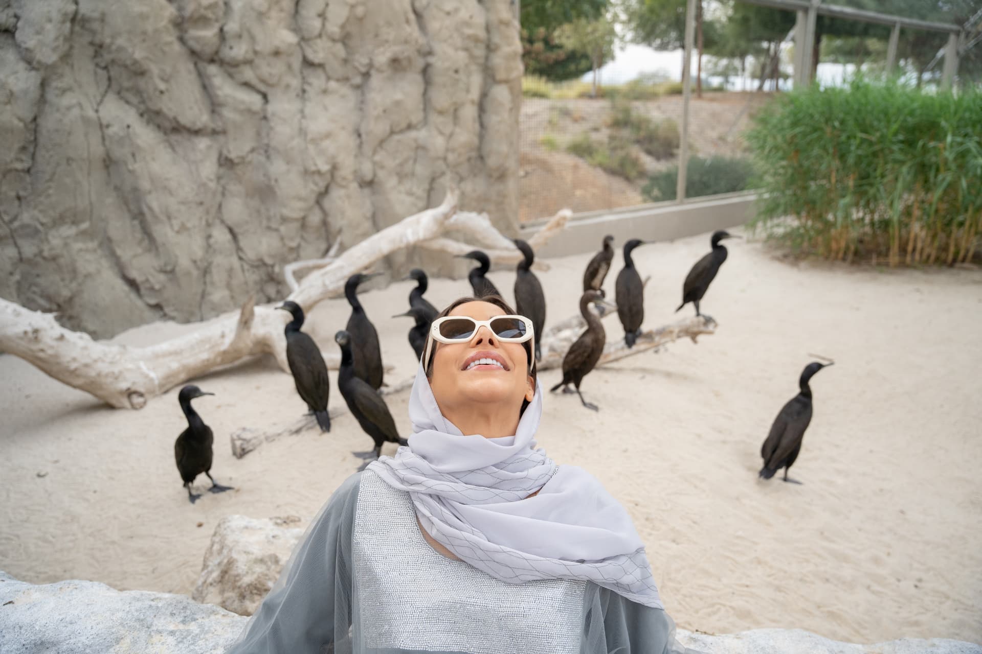 Woman in white sunglasses and headscarf among cormorants