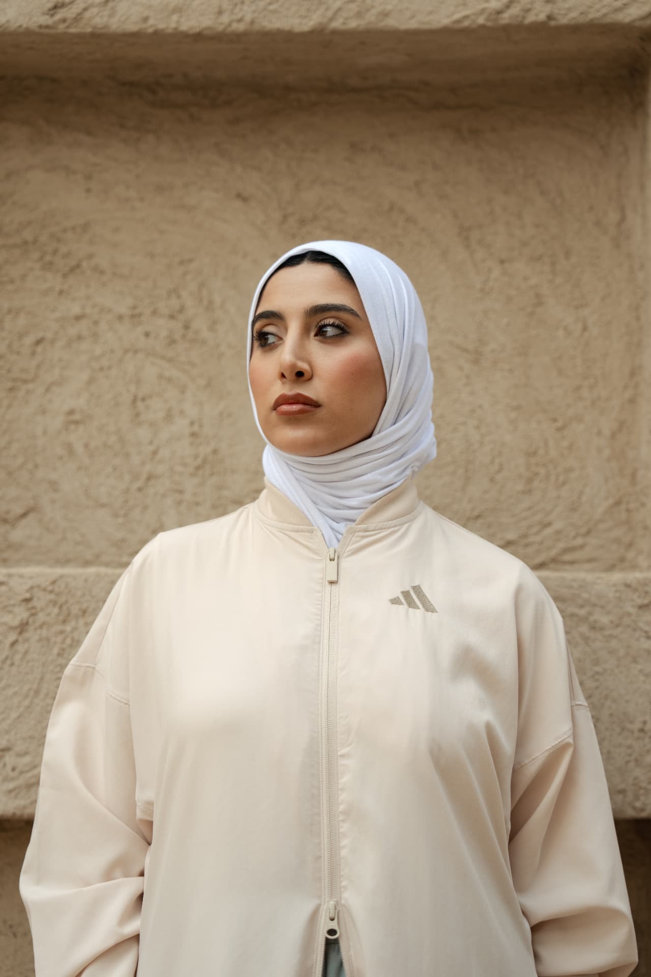Woman in a cream Adidas jacket and white hijab